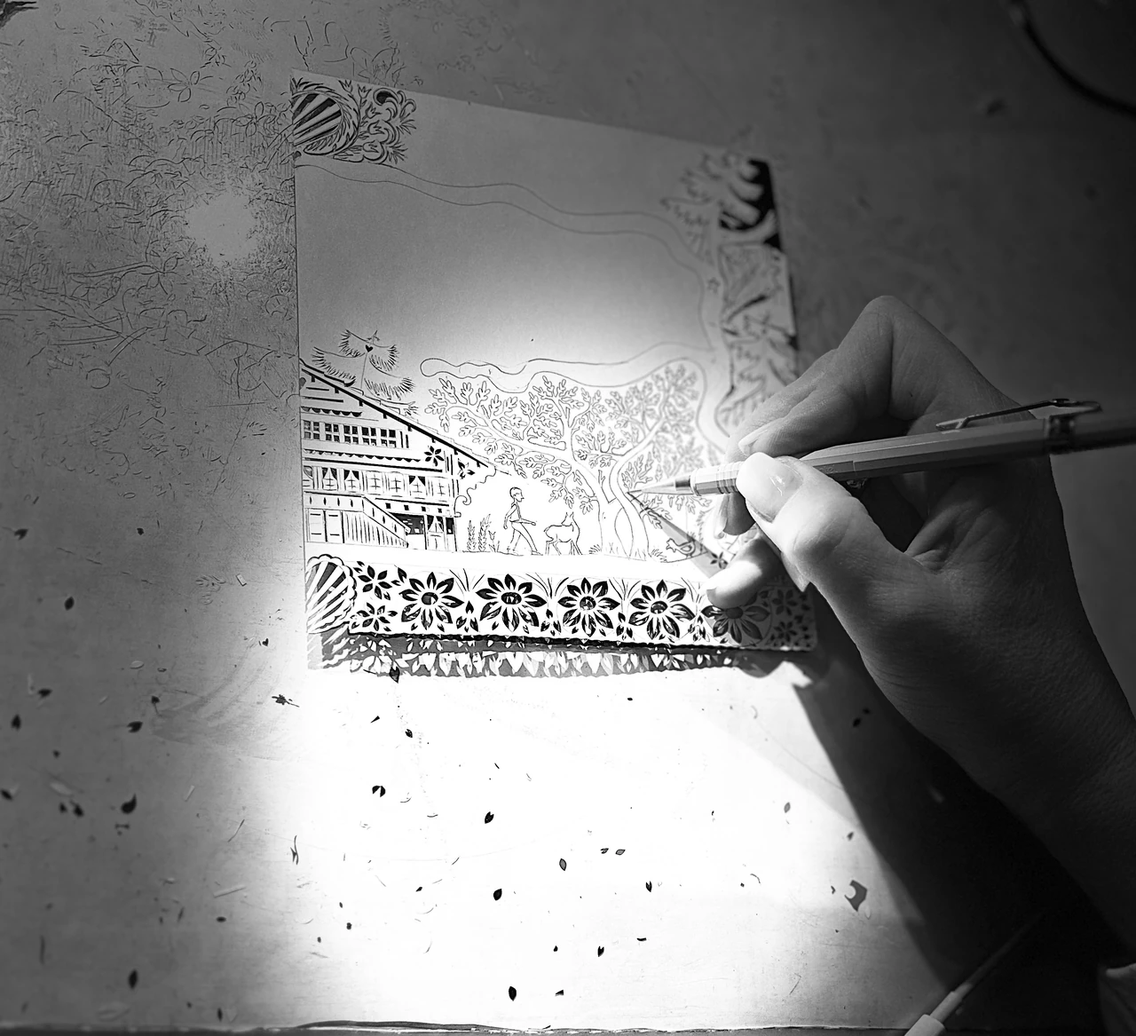 Mains au travail sur un découpage alpin en papier, en noir et blanc