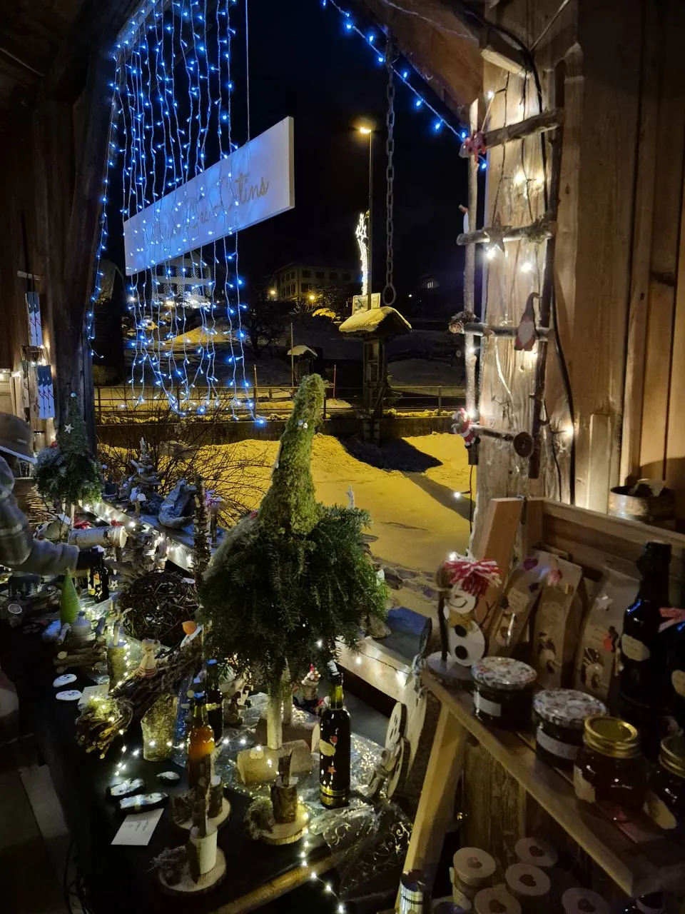 Décorations de Noël et guirlandes dans une grange ouverte sur le village enneigé, la nuit